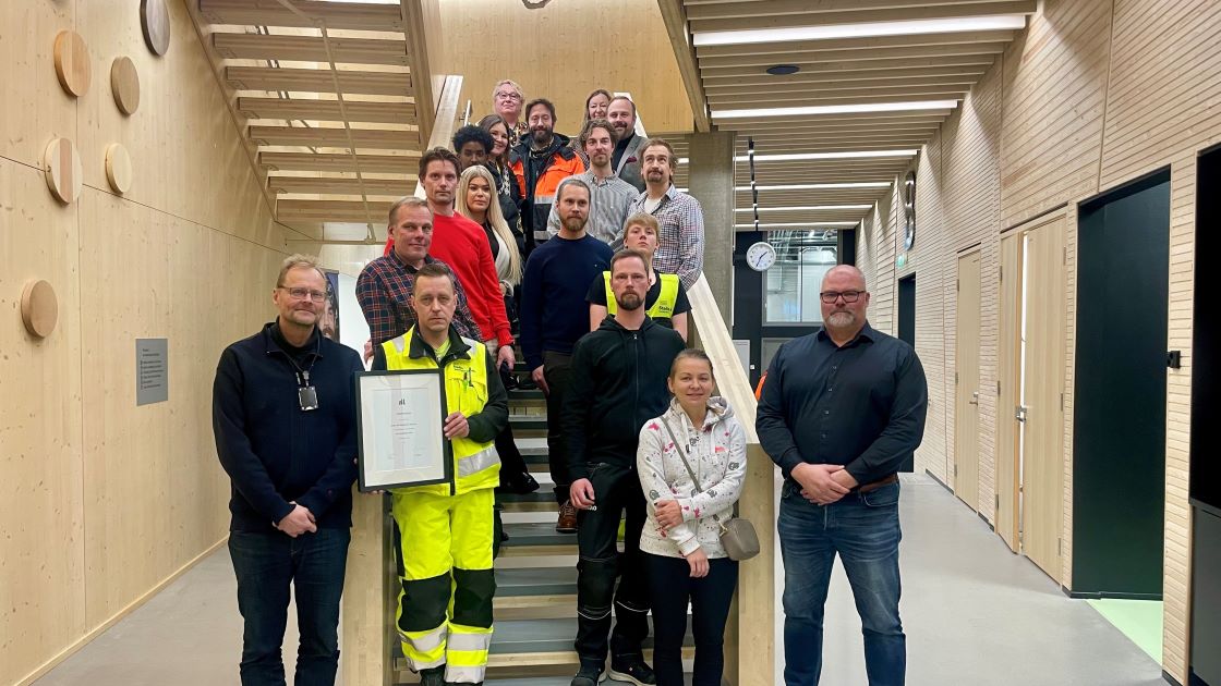 Palkitut ihmiset poseeraavat oppilaitoksen portailla kunniakirja yhden ihmisen käsissä.