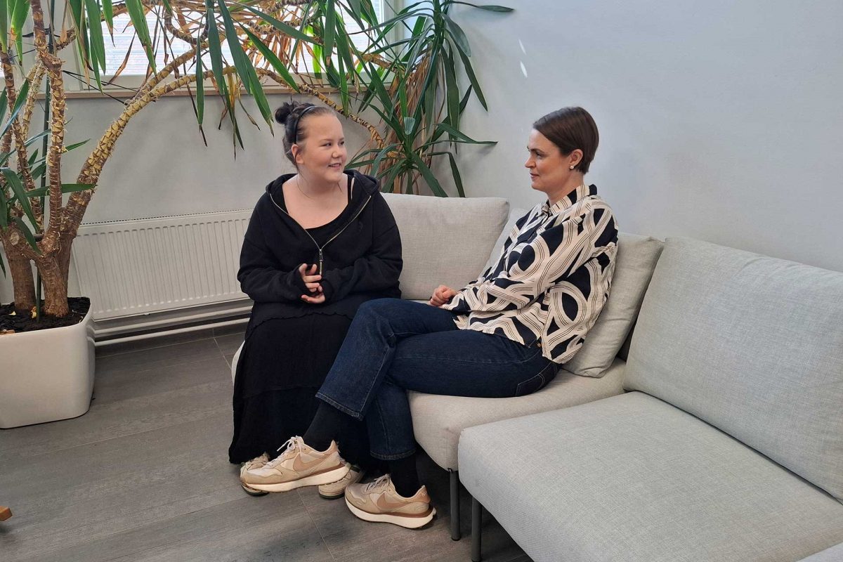 Oona juttelemassa opettajansa Katjan kanssa toimipaikan aulassa.