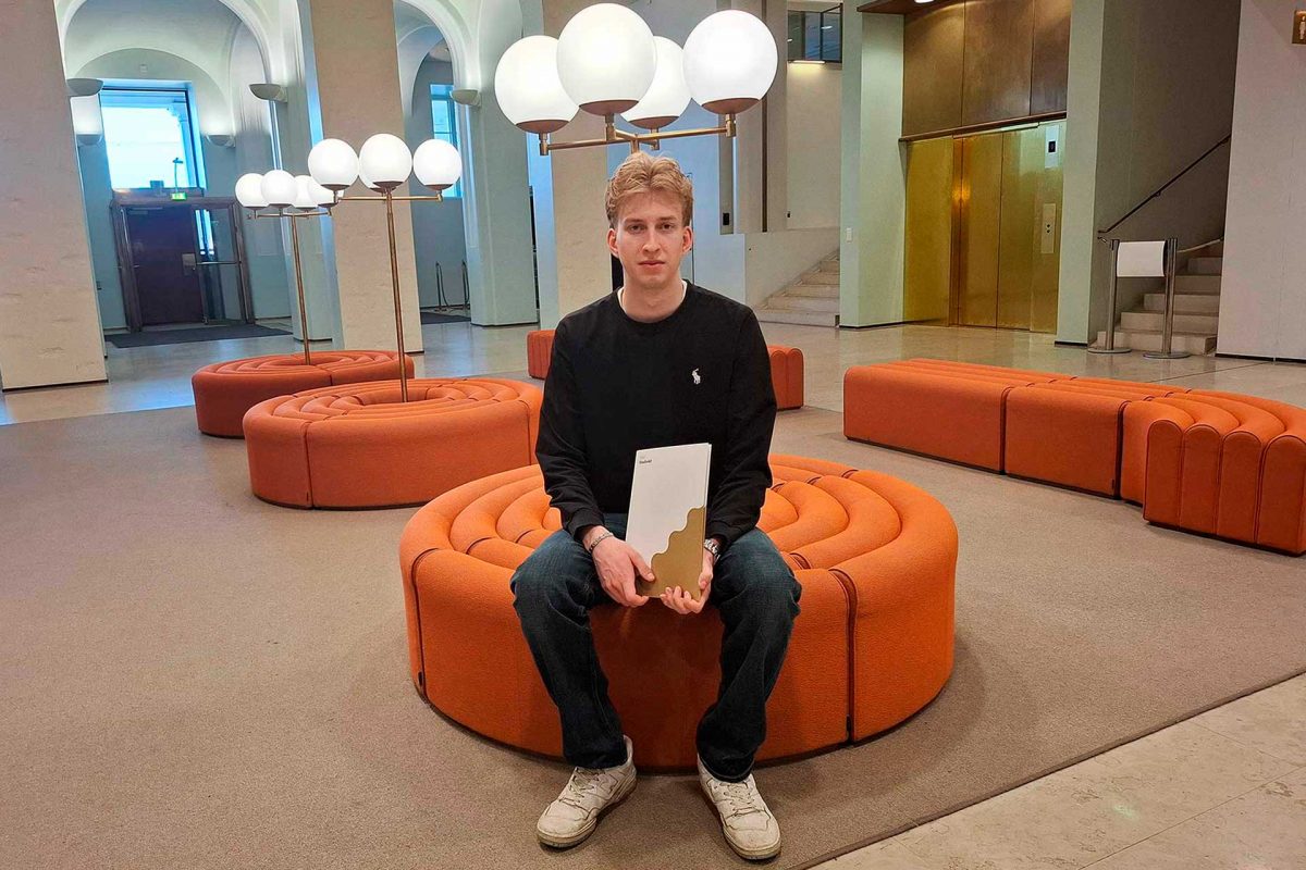 Otto Trebs istuu Helsingin kaupungintalon aulassa penkillä.
